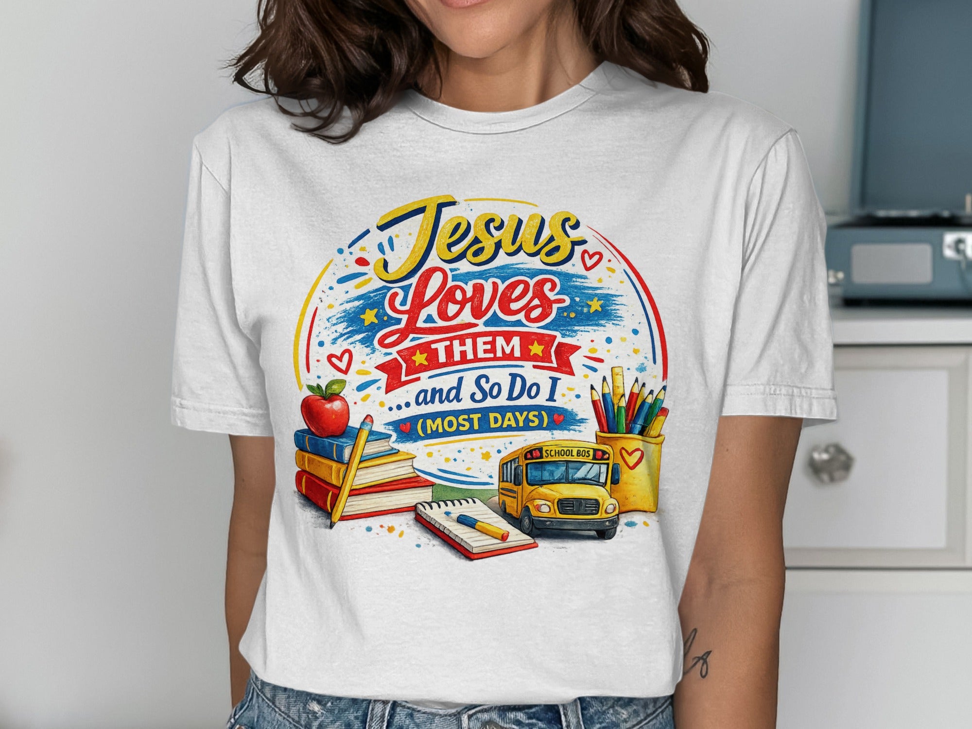 White t-shirt with "Jesus Loves Them...And So Do I" and school-themed illustration.