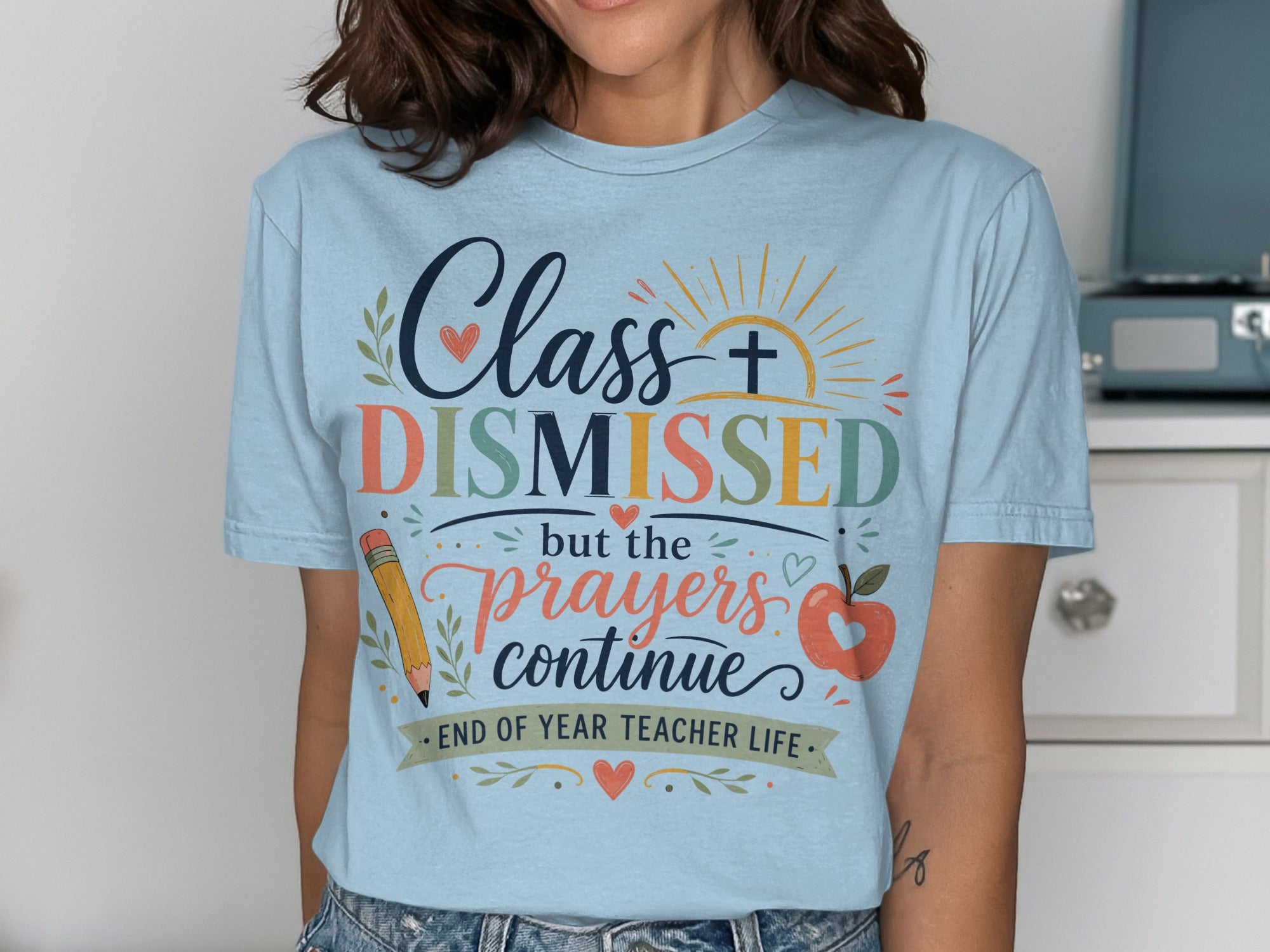 Light blue t-shirt with "Class Dismissed but the prayers continue" and apple/pencil design.