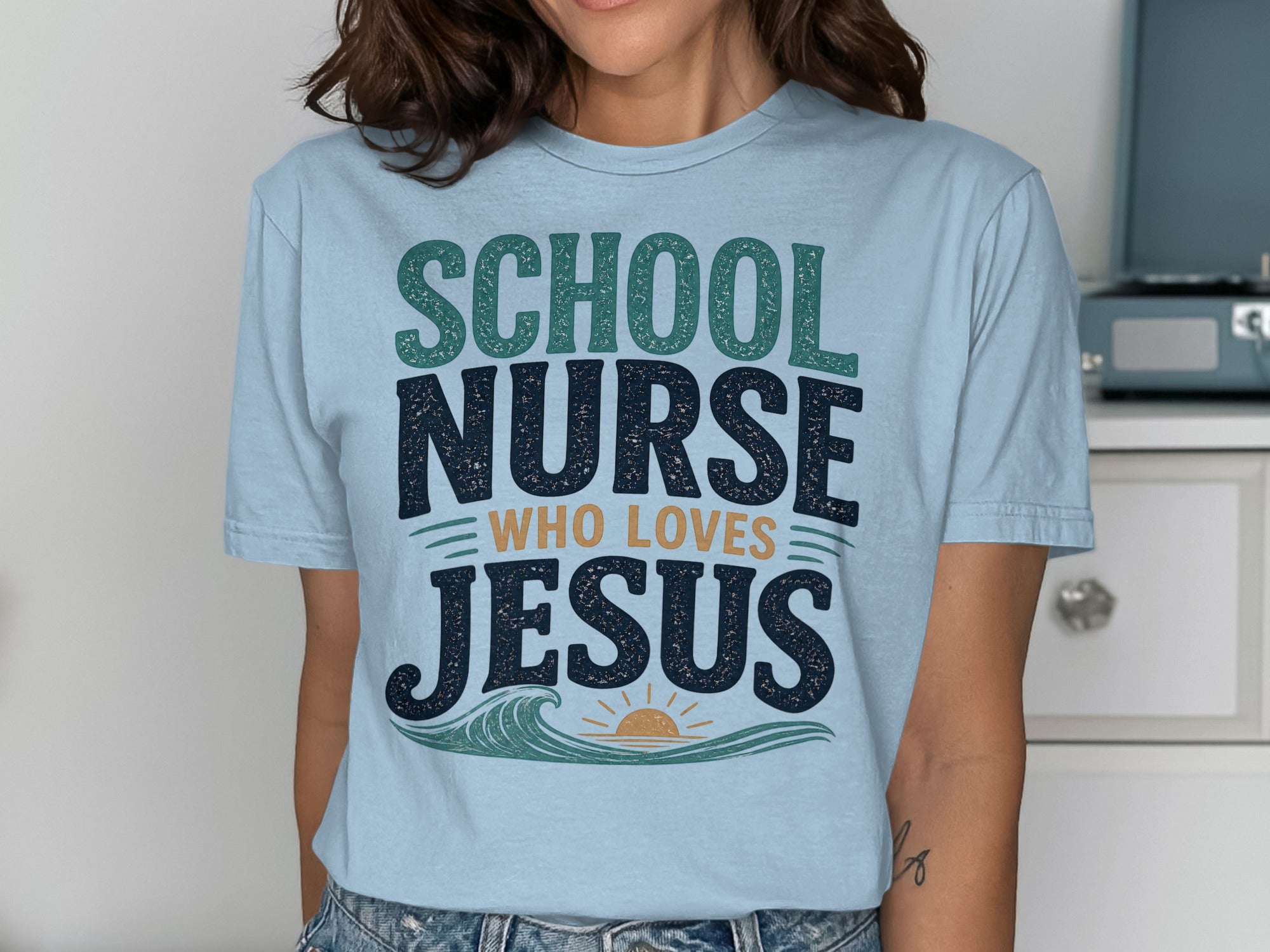 Light blue t-shirt with "SCHOOL NURSE WHO LOVES JESUS" text and wavy sun graphic.