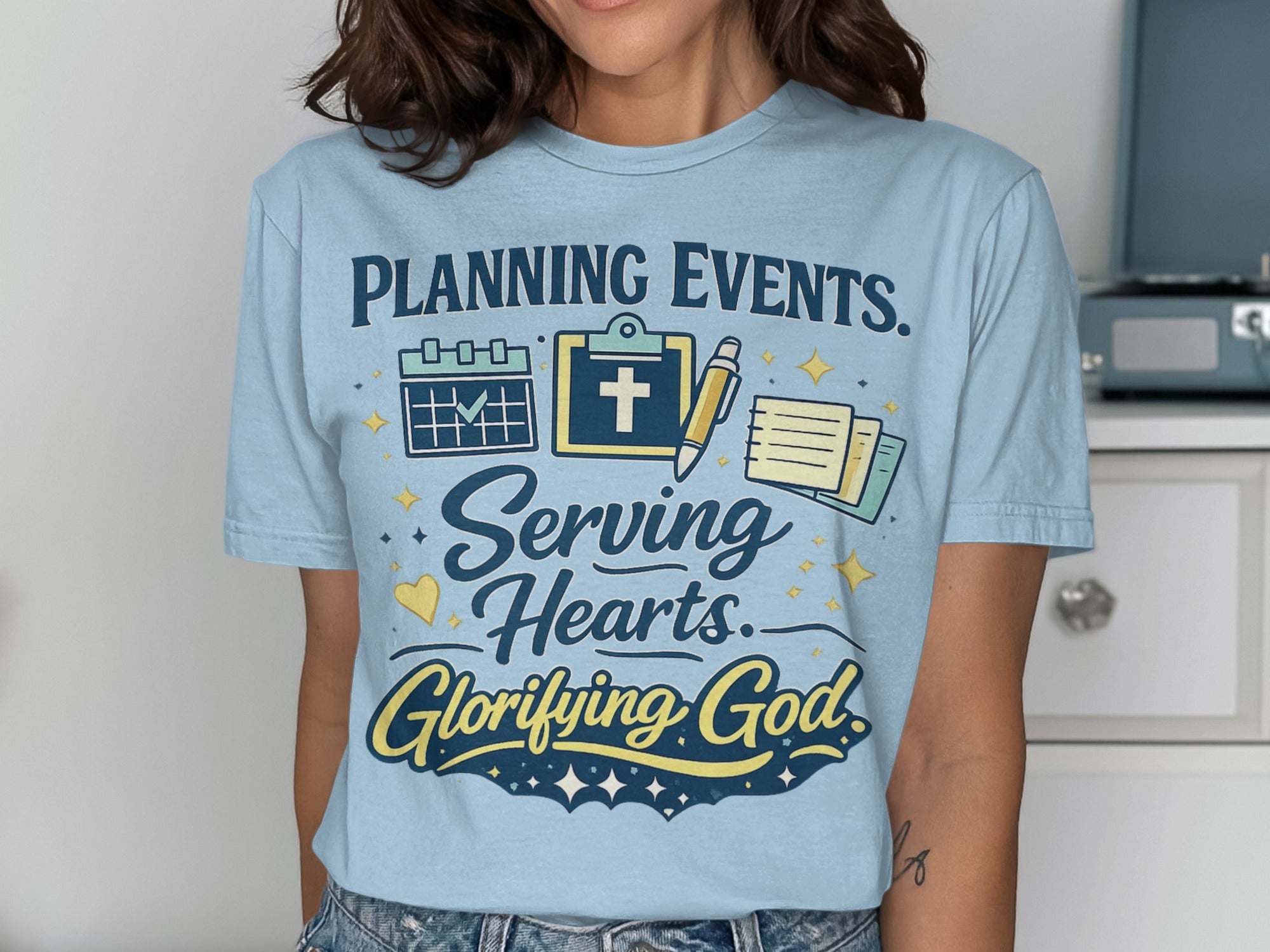 Light blue t-shirt with text "PLANNING EVENTS. Serving Hearts. Glorifying God."