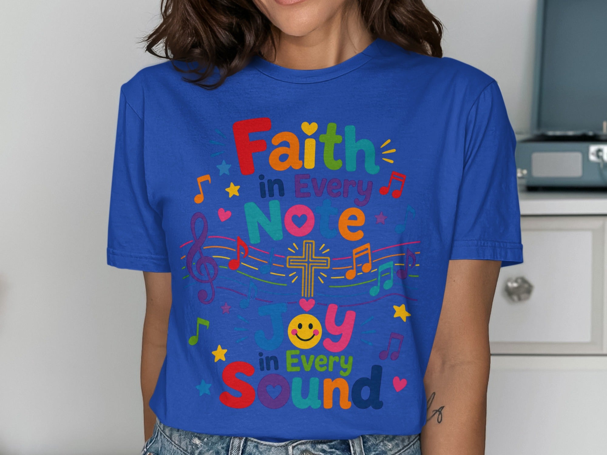 Blue t-shirt with colorful text and music notes saying "Faith in Every Note, Joy in Every Sound".