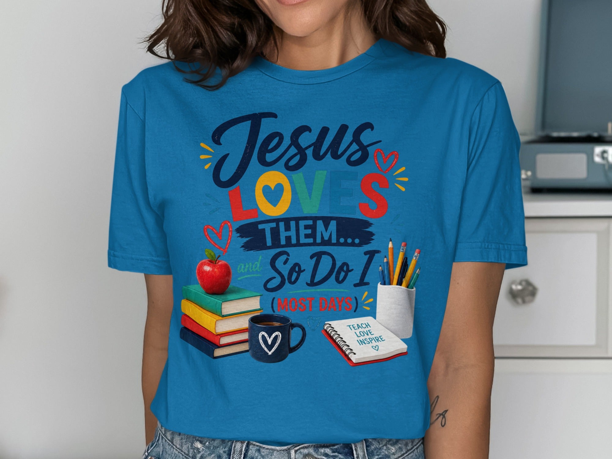 Blue t-shirt with "Jesus LOVES THEM... So Do I (MOST DAYS)" text and school supplies.