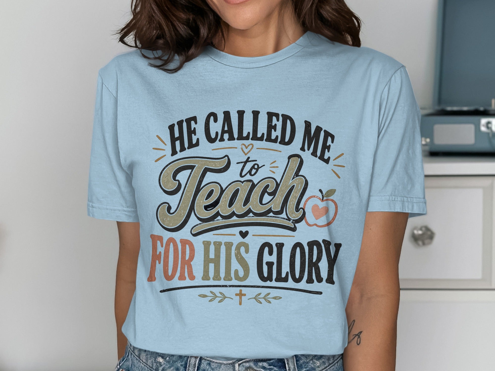 Light blue t-shirt with text "HE CALLED ME to Teach FOR HIS GLORY" and small apple graphic.