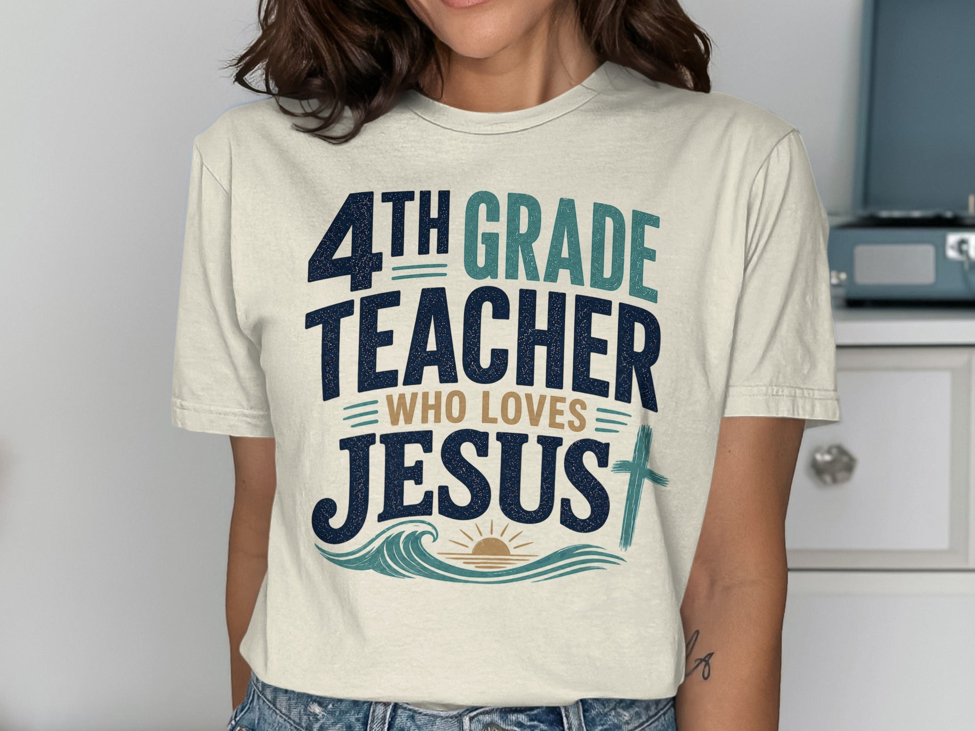 4th Grade Teacher Who Loves Jesus t-shirt with blue and green text and a cross.
