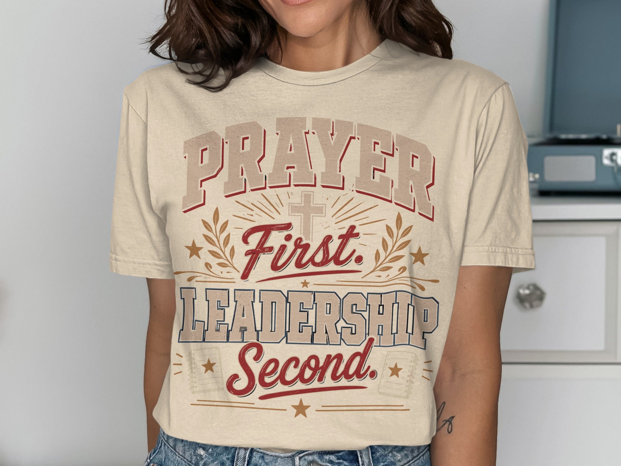 Cream t-shirt with "Prayer First, Leadership Second" text and cross graphic.