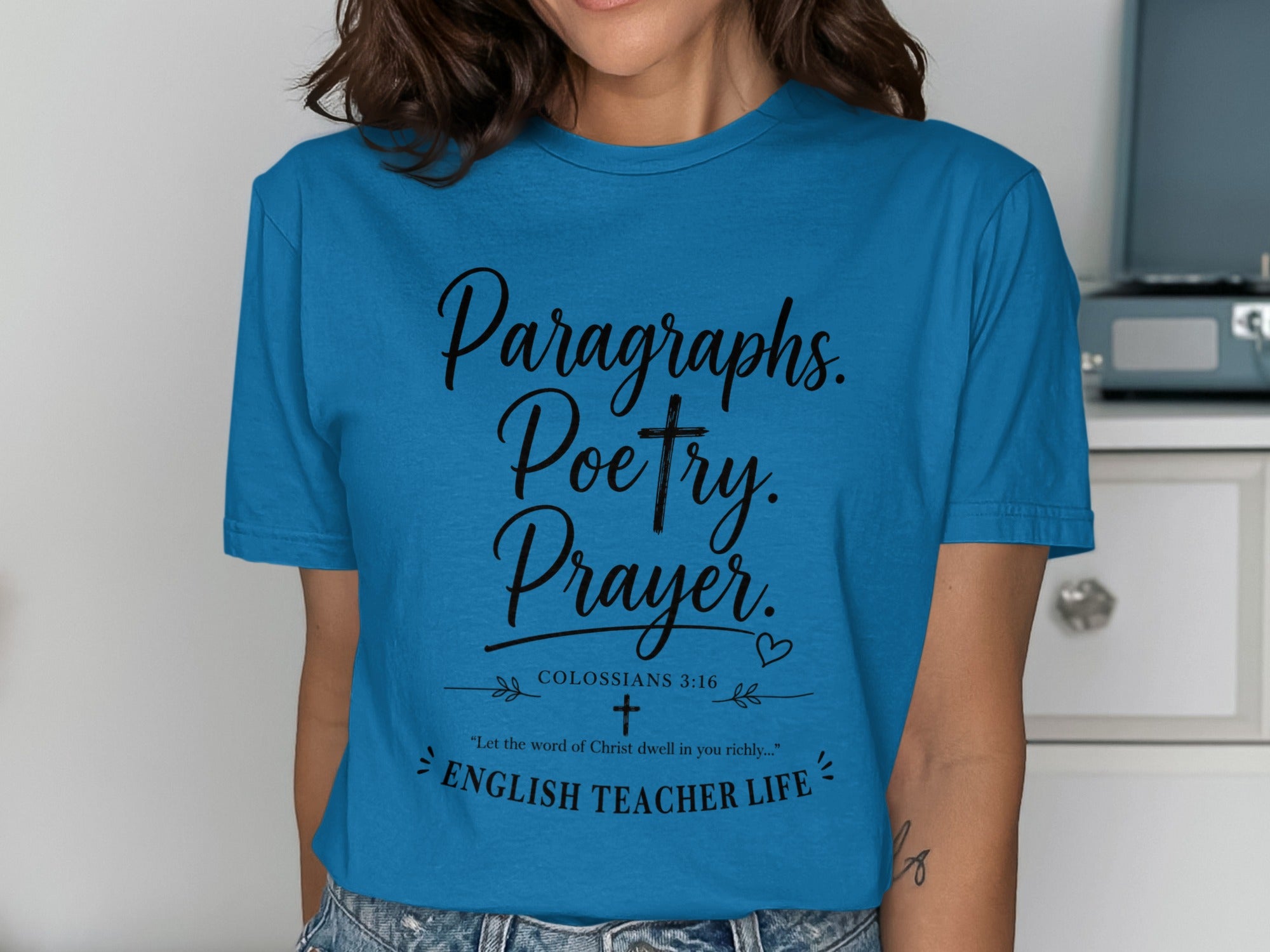 Blue t-shirt with "Paragraphs. Poetry. Prayer. COLOSSIANS 3:16 'Let the word of Christ dwell in you richly...' ENGLISH TEACHER LIFE" text.