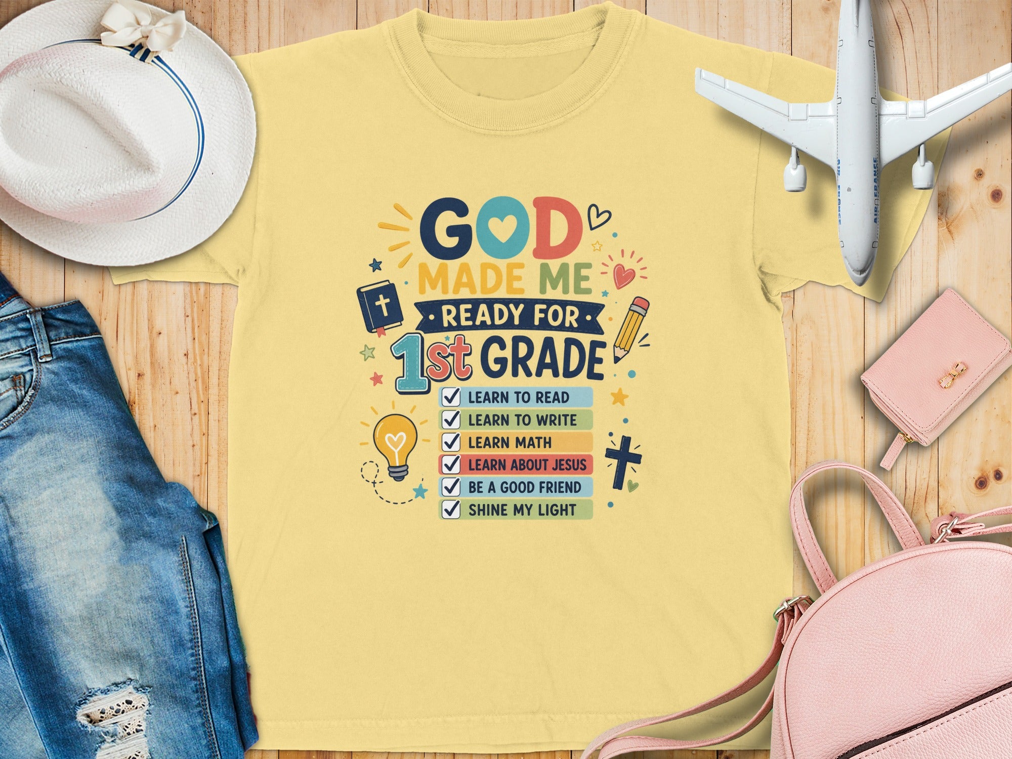 Yellow t-shirt with "God Made Me Ready for 1st Grade" and learning checklist.