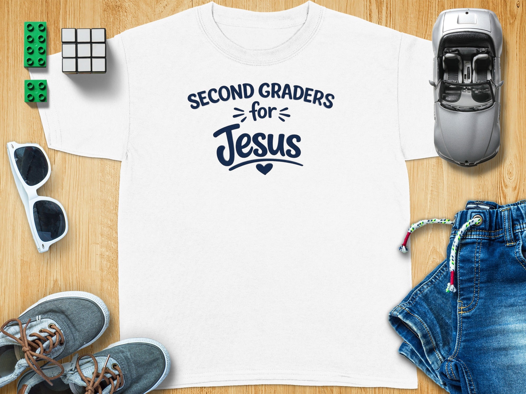 White t-shirt with "Second Graders for Jesus" text, surrounded by toys and clothing.