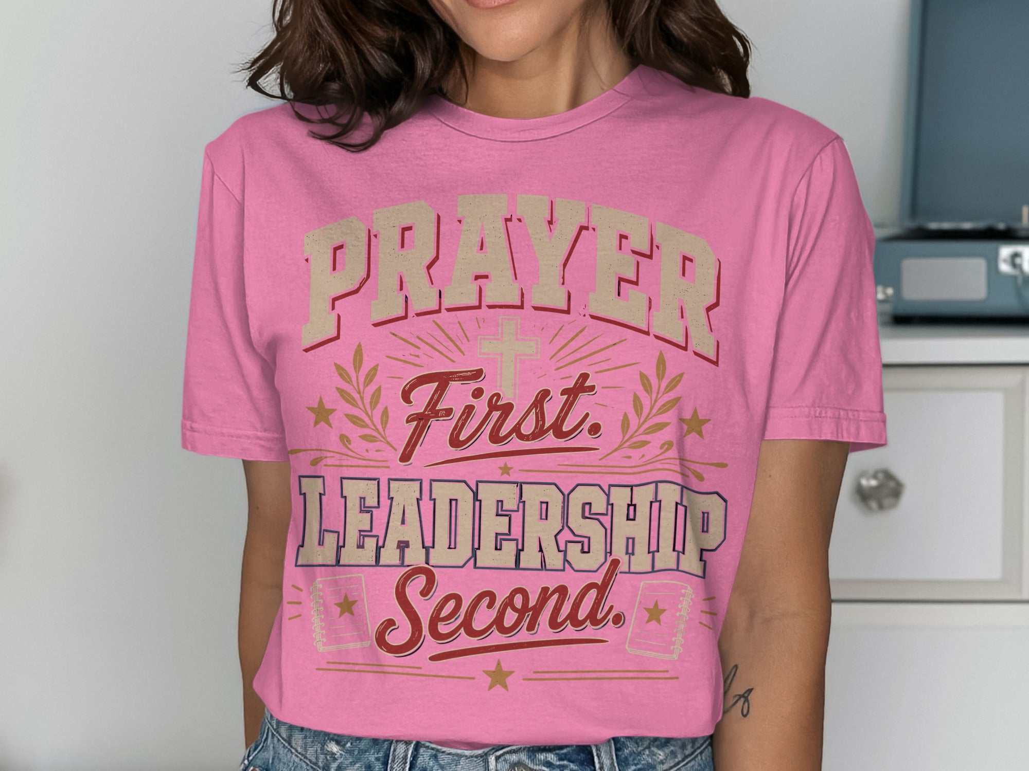Pink t-shirt with "Prayer First. Leadership Second." text and religious imagery.