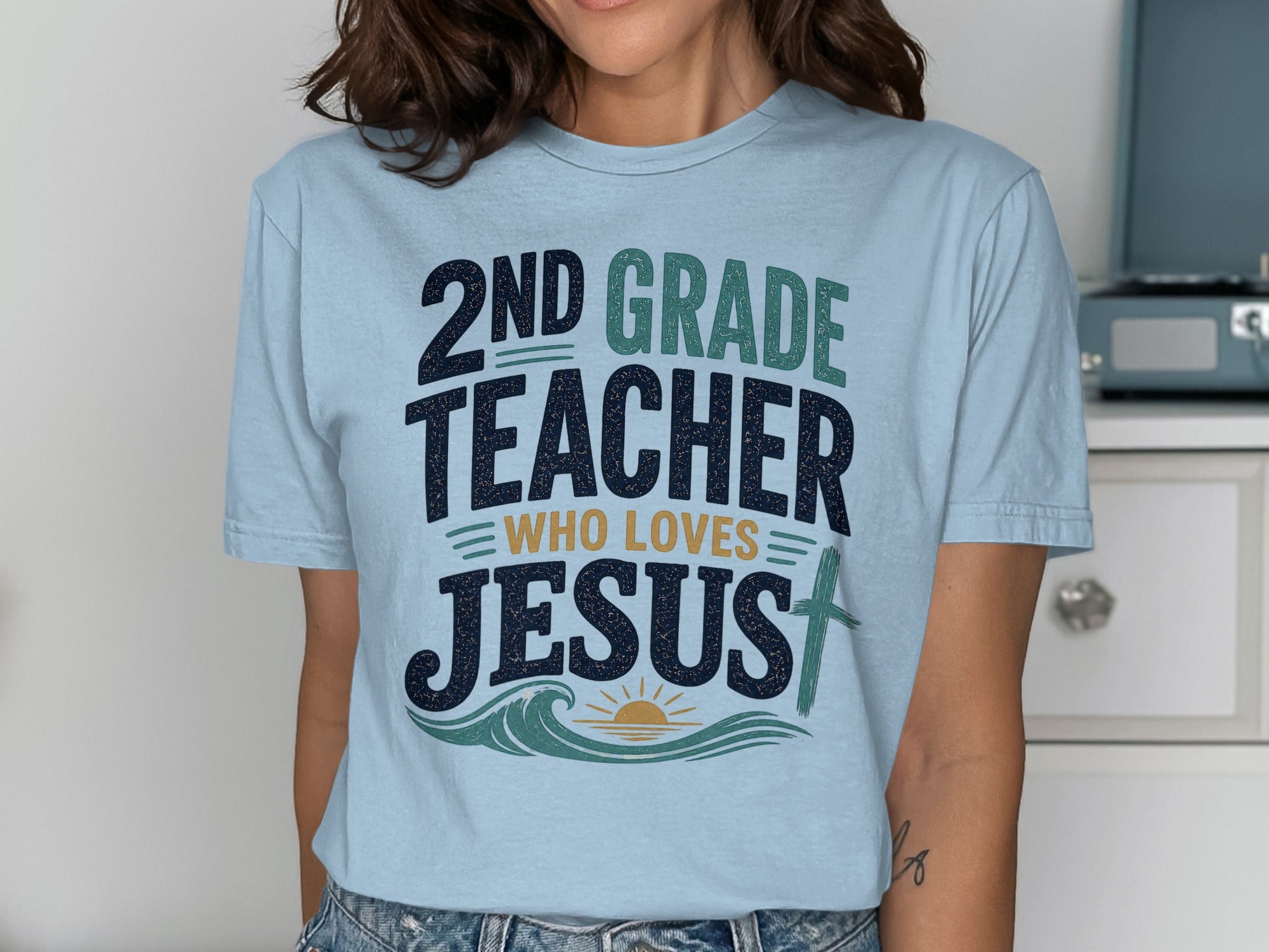 Light blue t-shirt with "2nd Grade Teacher Who Loves Jesus" text and graphics.