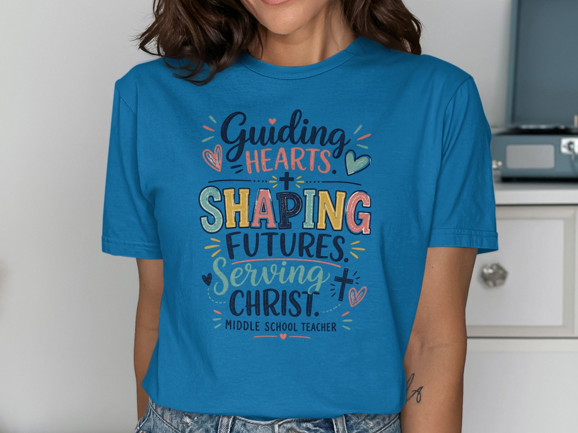 Blue t-shirt with "Guiding Hearts, Shaping Futures, Serving Christ" text.