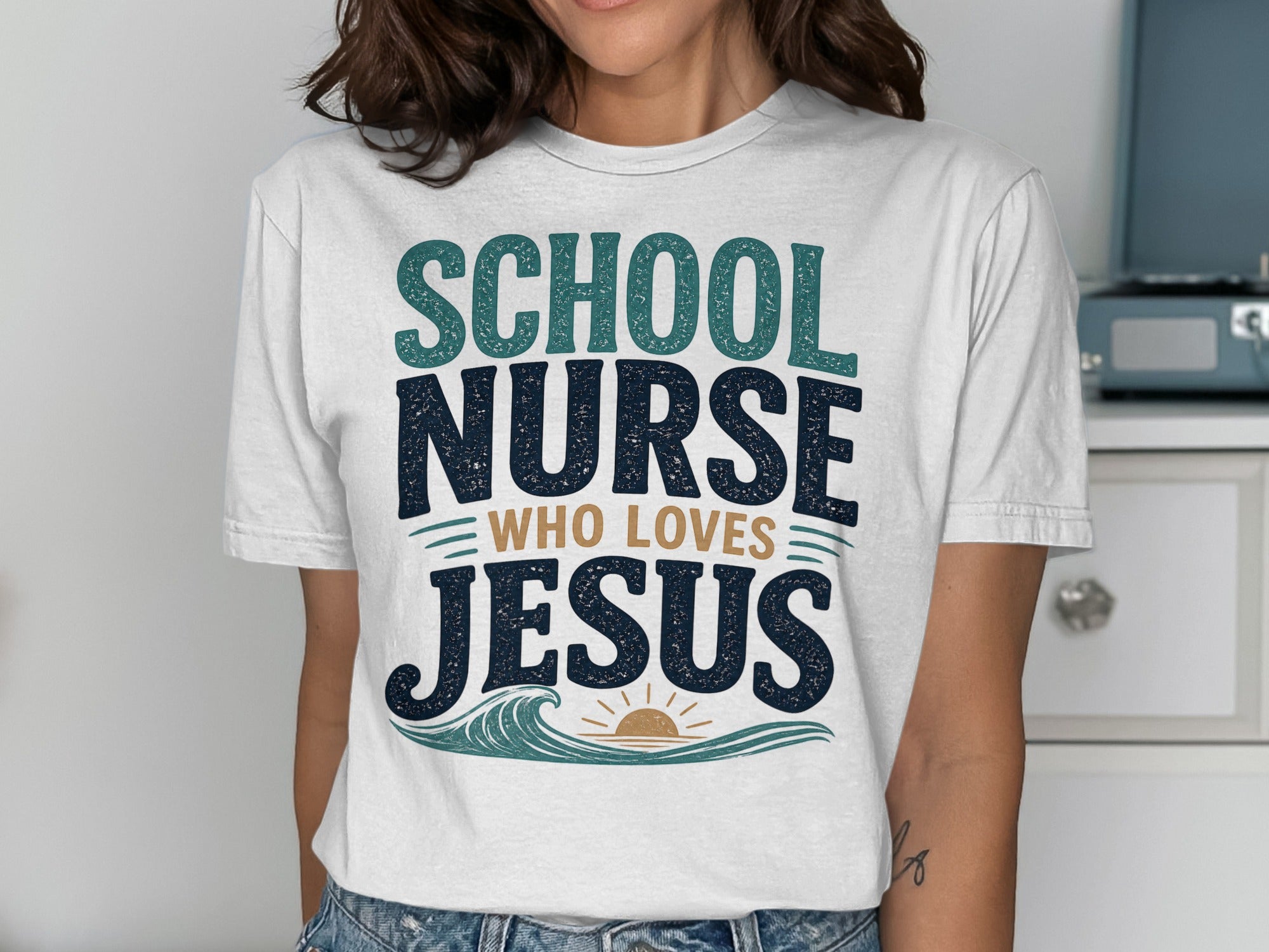 White t-shirt with "SCHOOL NURSE WHO LOVES JESUS" in blue and green lettering.