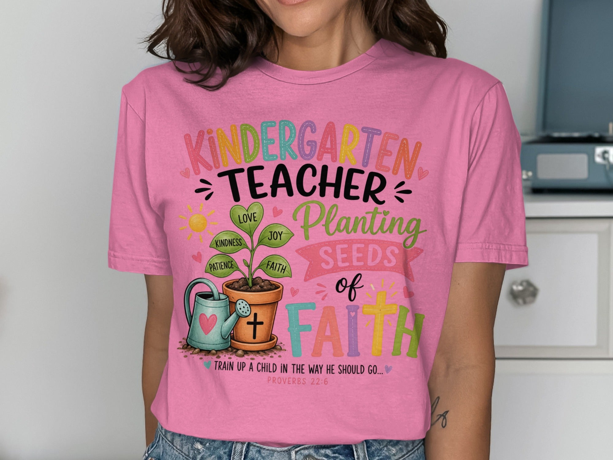 Pink t-shirt with "Kindergarten Teacher Planting Seeds of Faith" graphic.