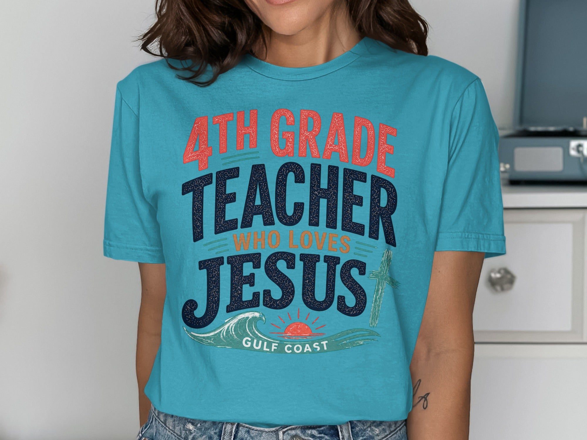 Teal t-shirt with "4th grade teacher who loves Jesus" and cross graphic.