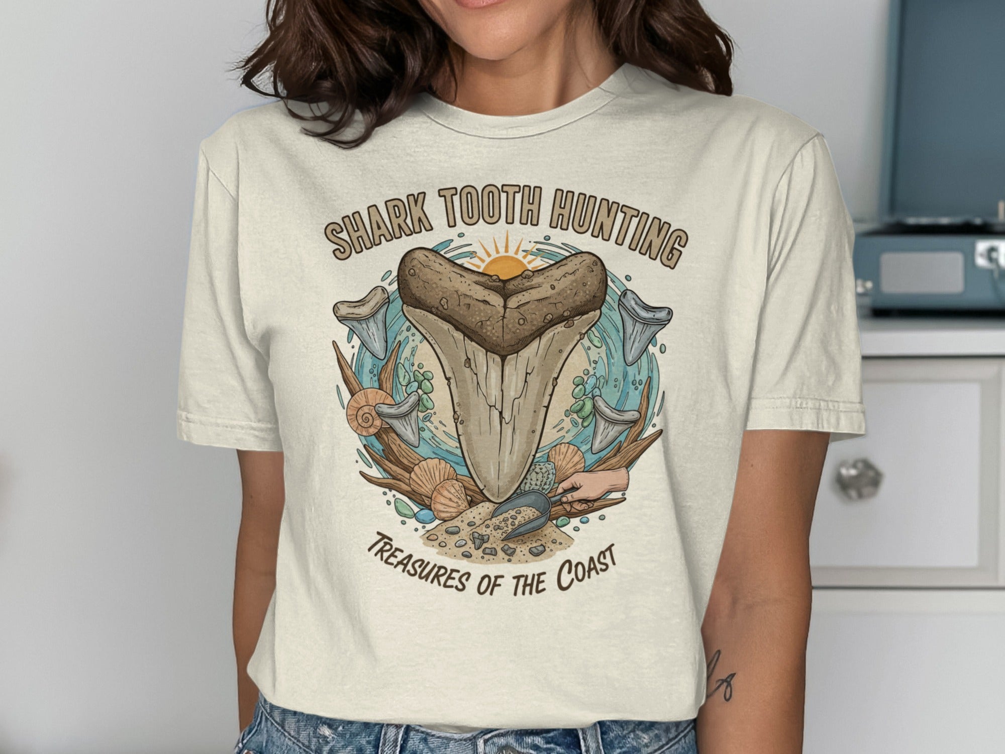 Shark Tooth Hunting Treasures of the Coast graphic on a cream t-shirt.