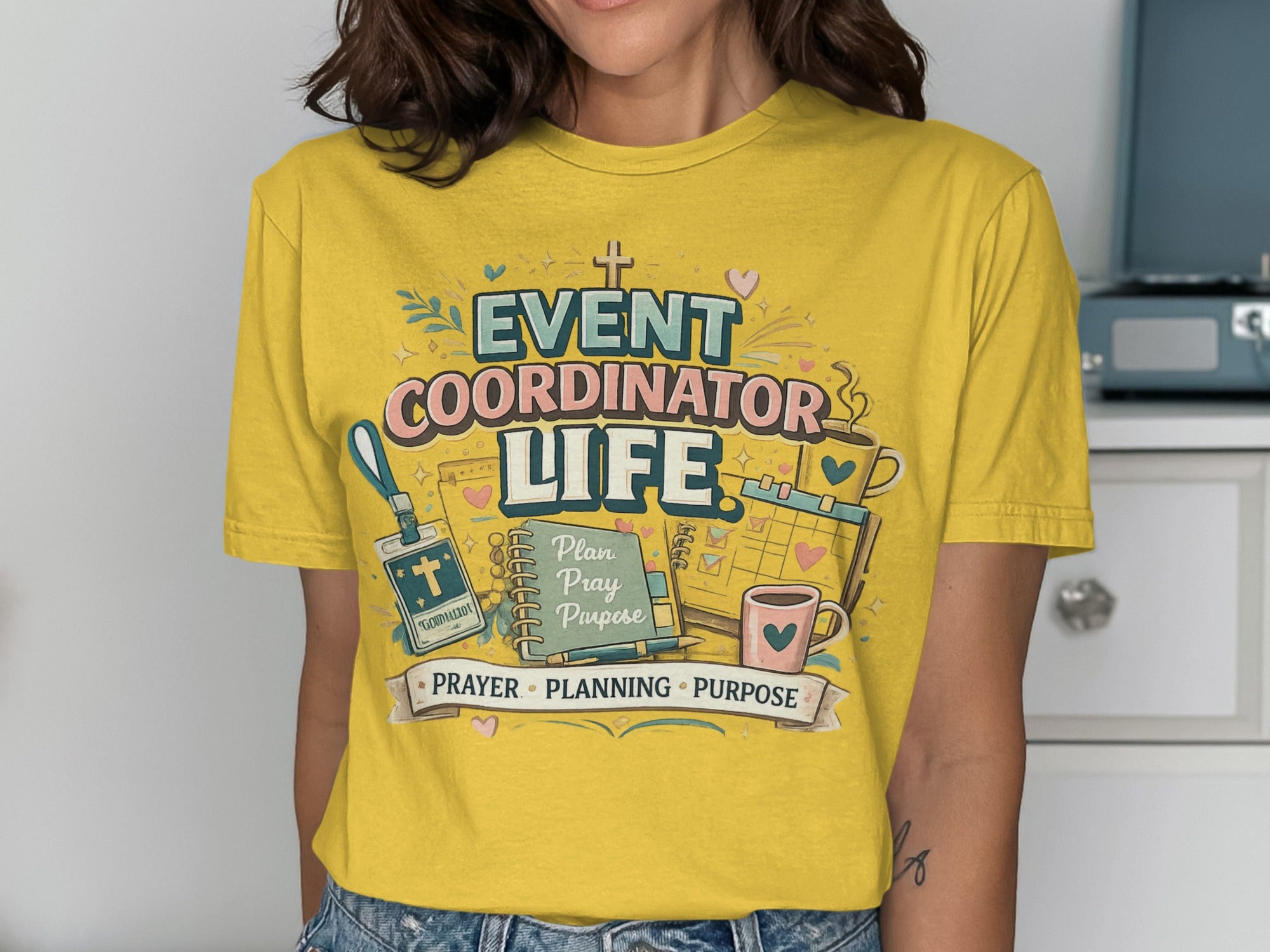 Yellow t-shirt with "Event Coordinator Life" design, planner, and coffee cup.