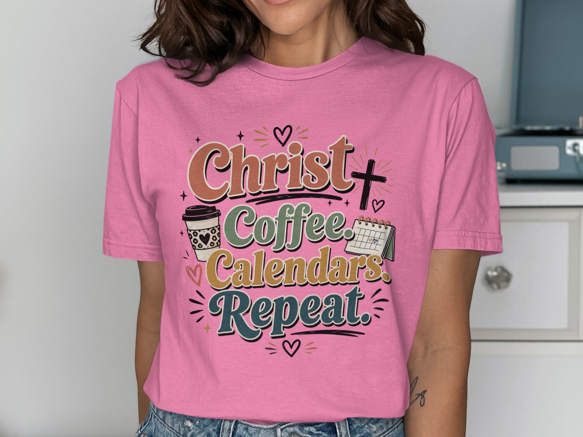 Pink t-shirt with "Christ. Coffee. Calendars. Repeat." text and coffee cup graphic.