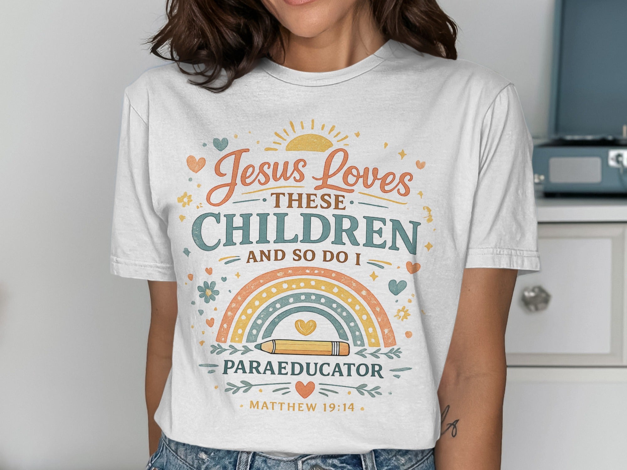 T-shirt with "Jesus Loves These Children And So Do I Paraeducator" and rainbow design.