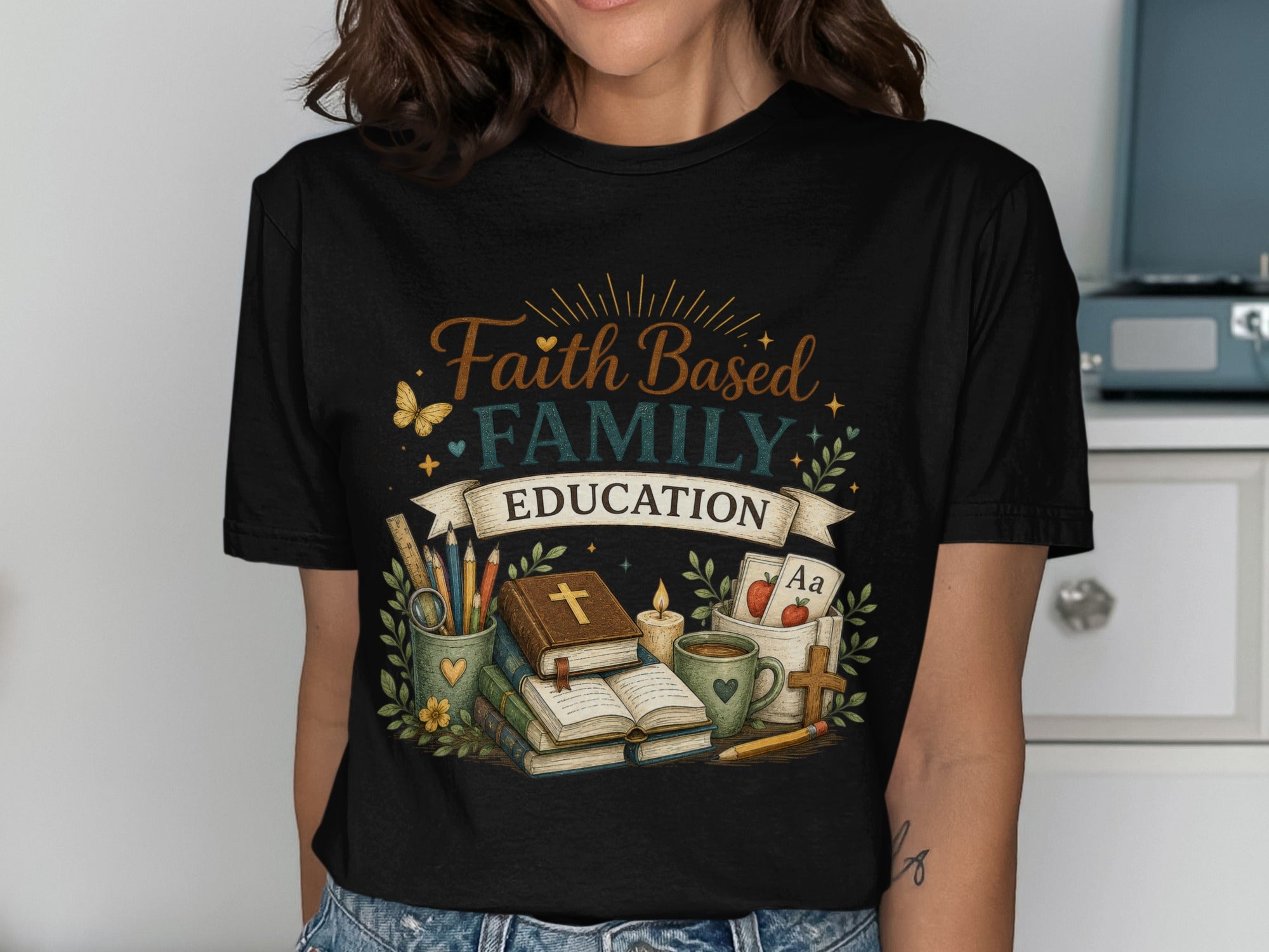 Faith Family Education graphic on a black t-shirt with books, pencils, and alphabet cards.