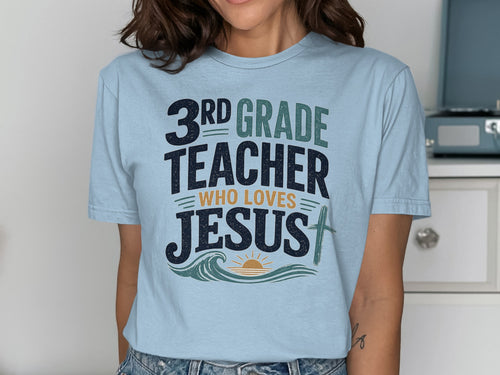 Light blue t-shirt with "3rd Grade Teacher Who Loves Jesus" text and wave graphics.