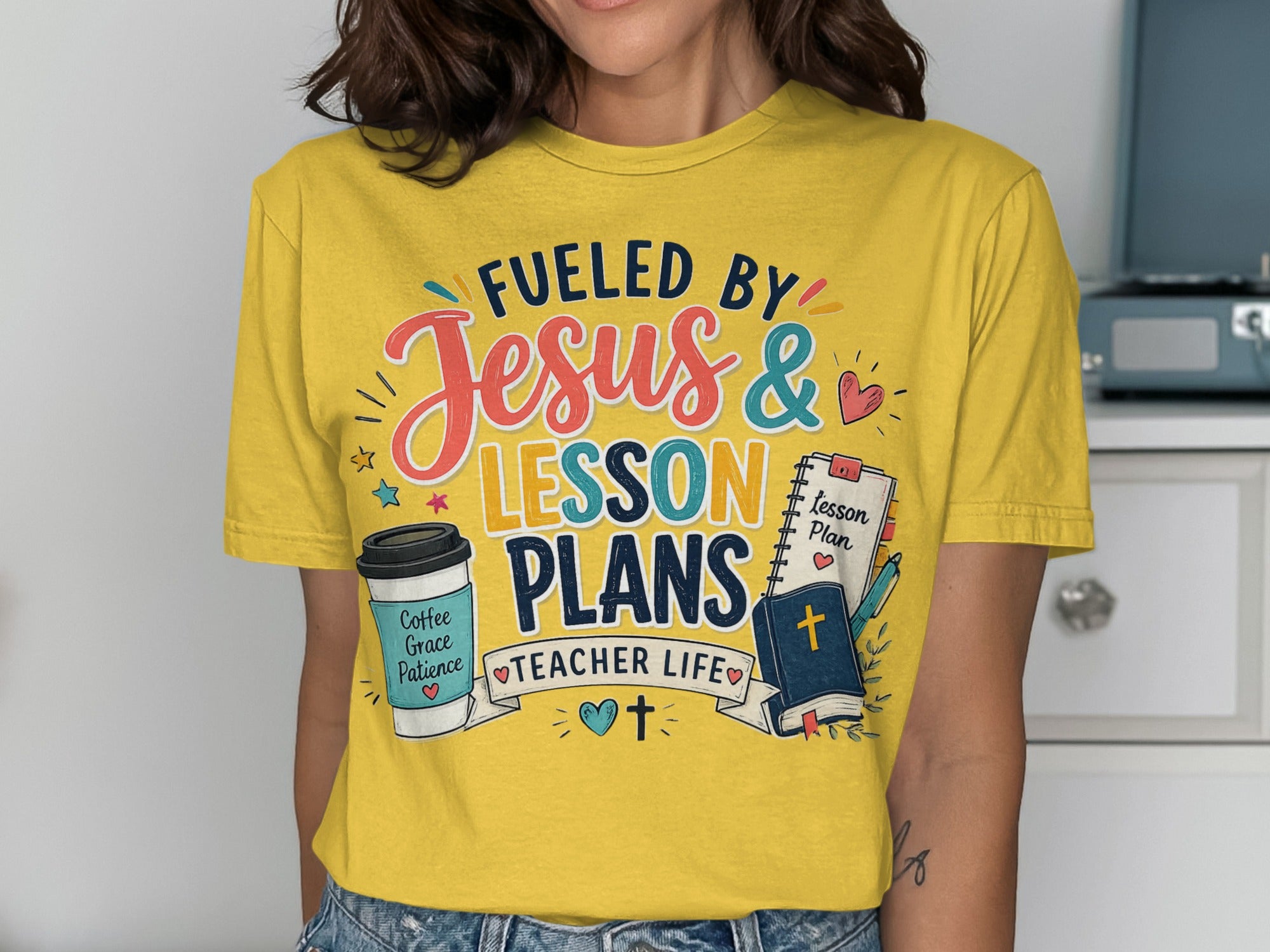 Yellow t-shirt with "Fueled by Jesus & Lesson Plans" graphic and teacher-themed icons.