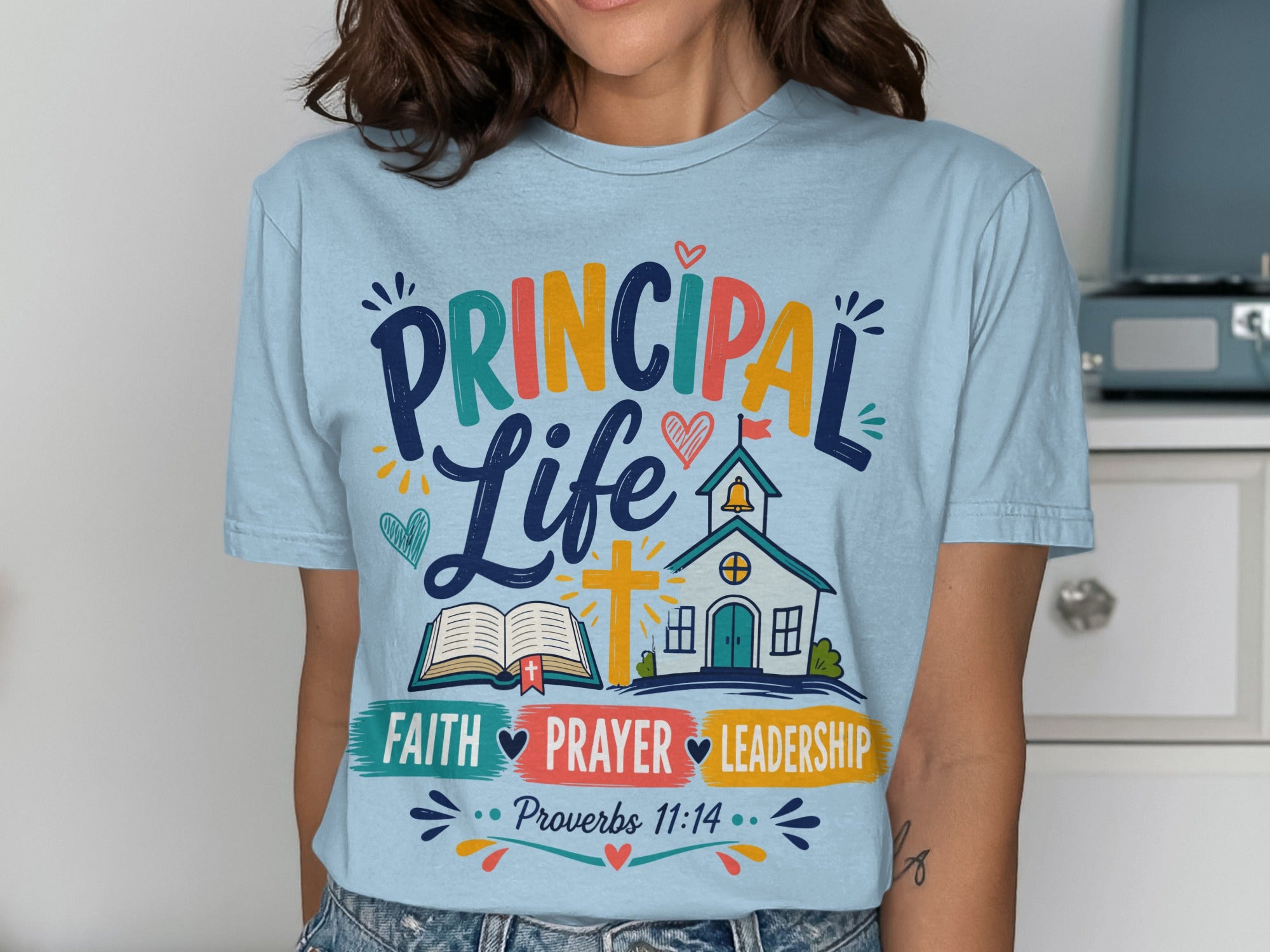Light blue t-shirt with "Principal Life" text and religious symbols.