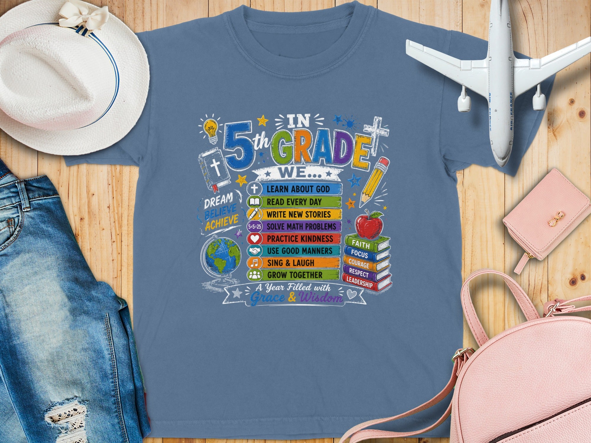 Blue t-shirt graphic for 5th grade with school supplies, books, and inspirational words.
