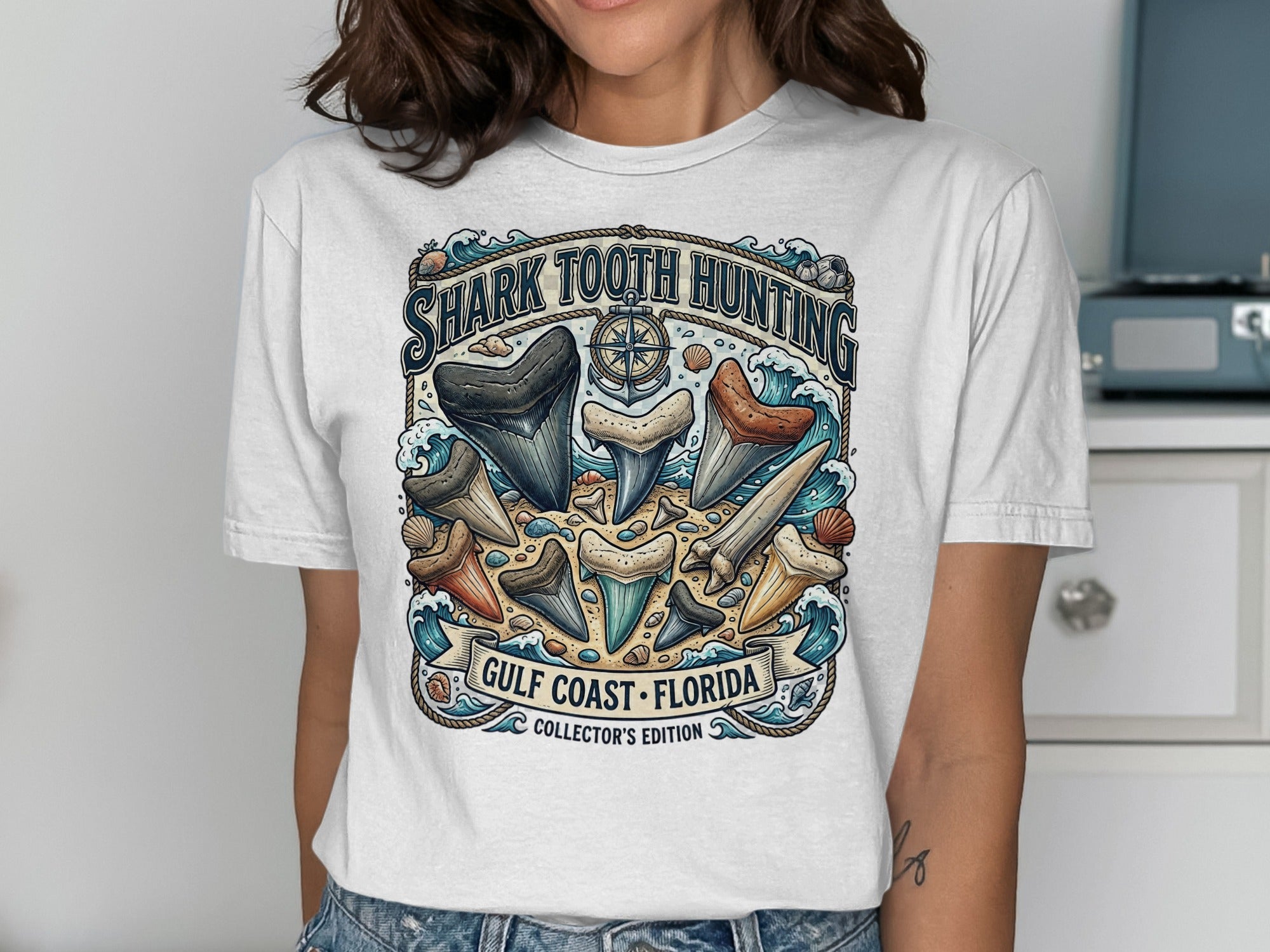 Graphic t-shirt with "Shark Tooth Hunting" and "Gulf Coast Florida" text, featuring shark teeth.