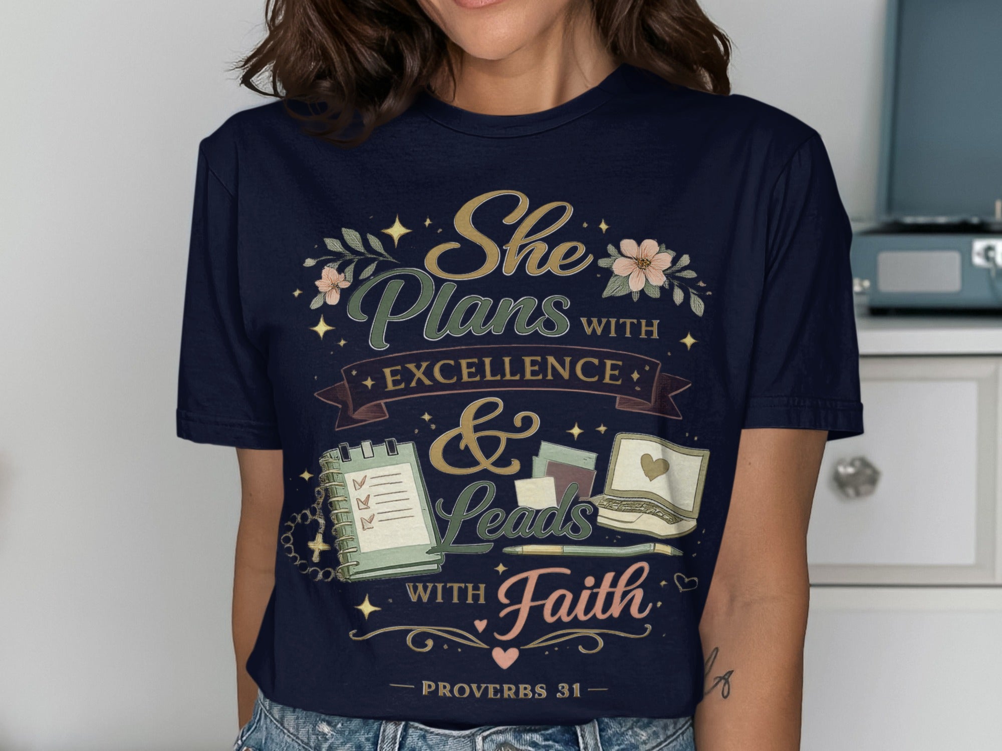 Navy t-shirt with "She Plans with Excellence & Leads with Faith" text and floral accents.