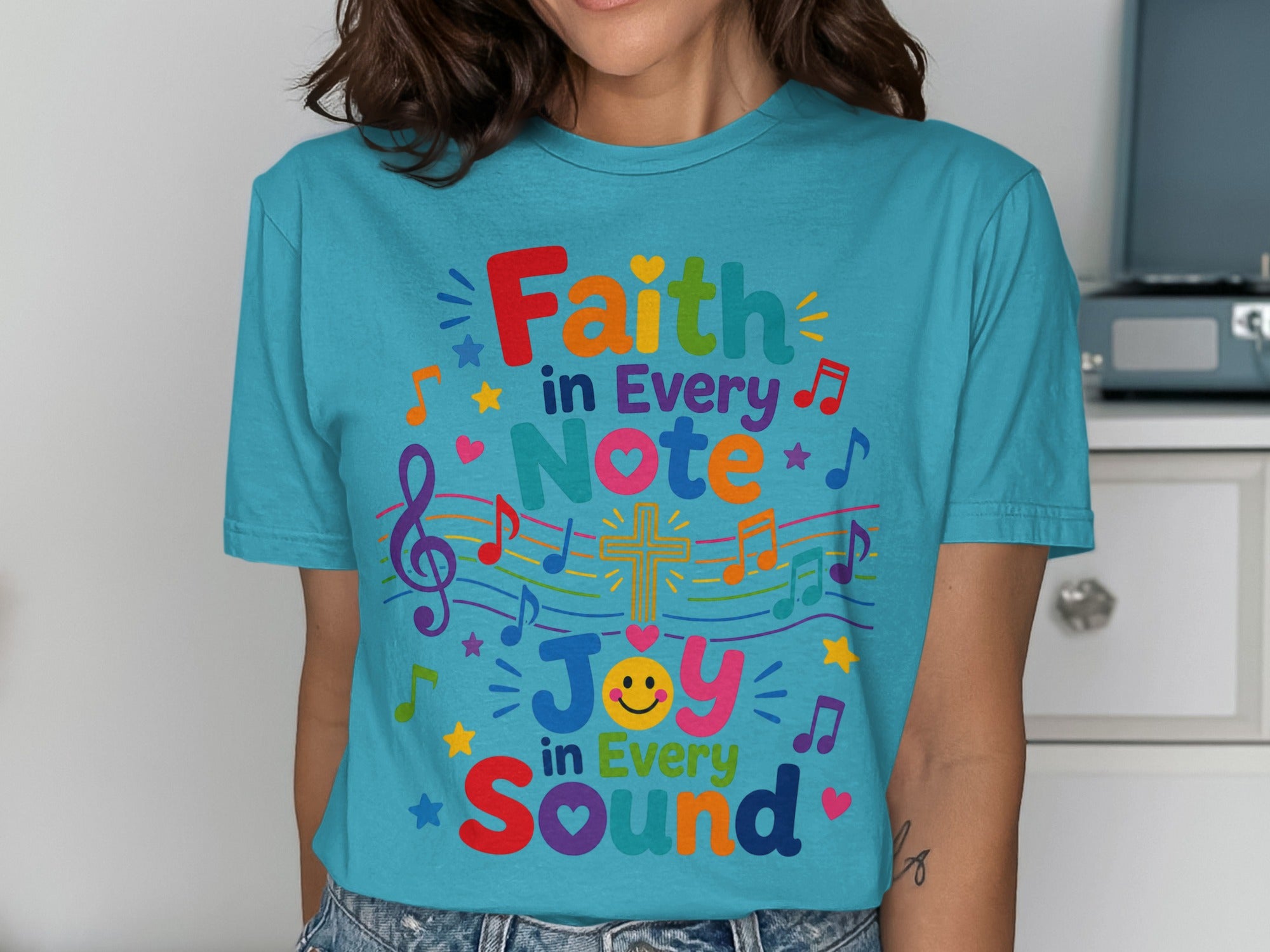 Teal t-shirt with "Faith in Every Note, Joy in Every Sound" text and musical notes.