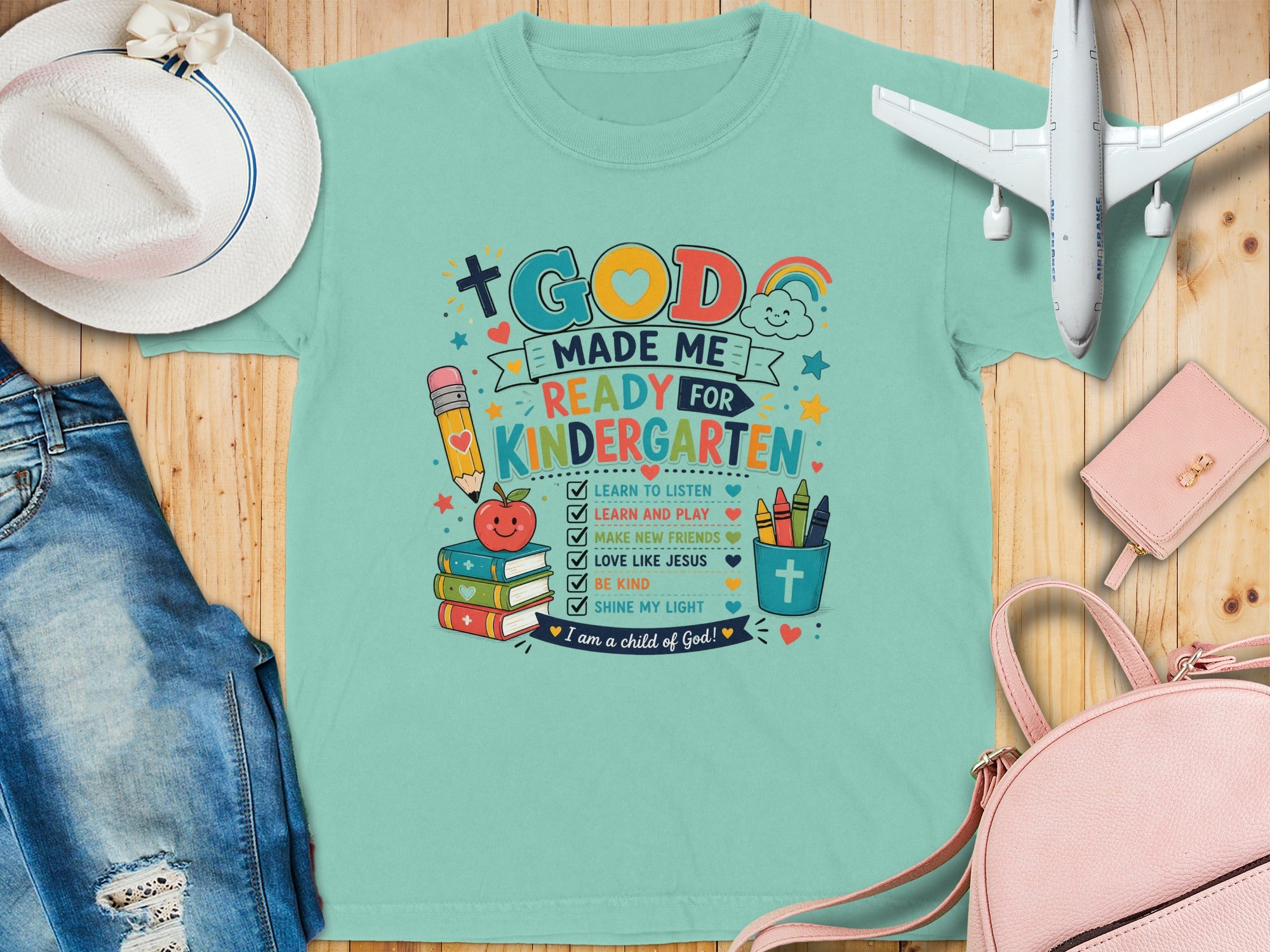 Mint t-shirt with "God Made Me Ready for Kindergarten" text and school icons.