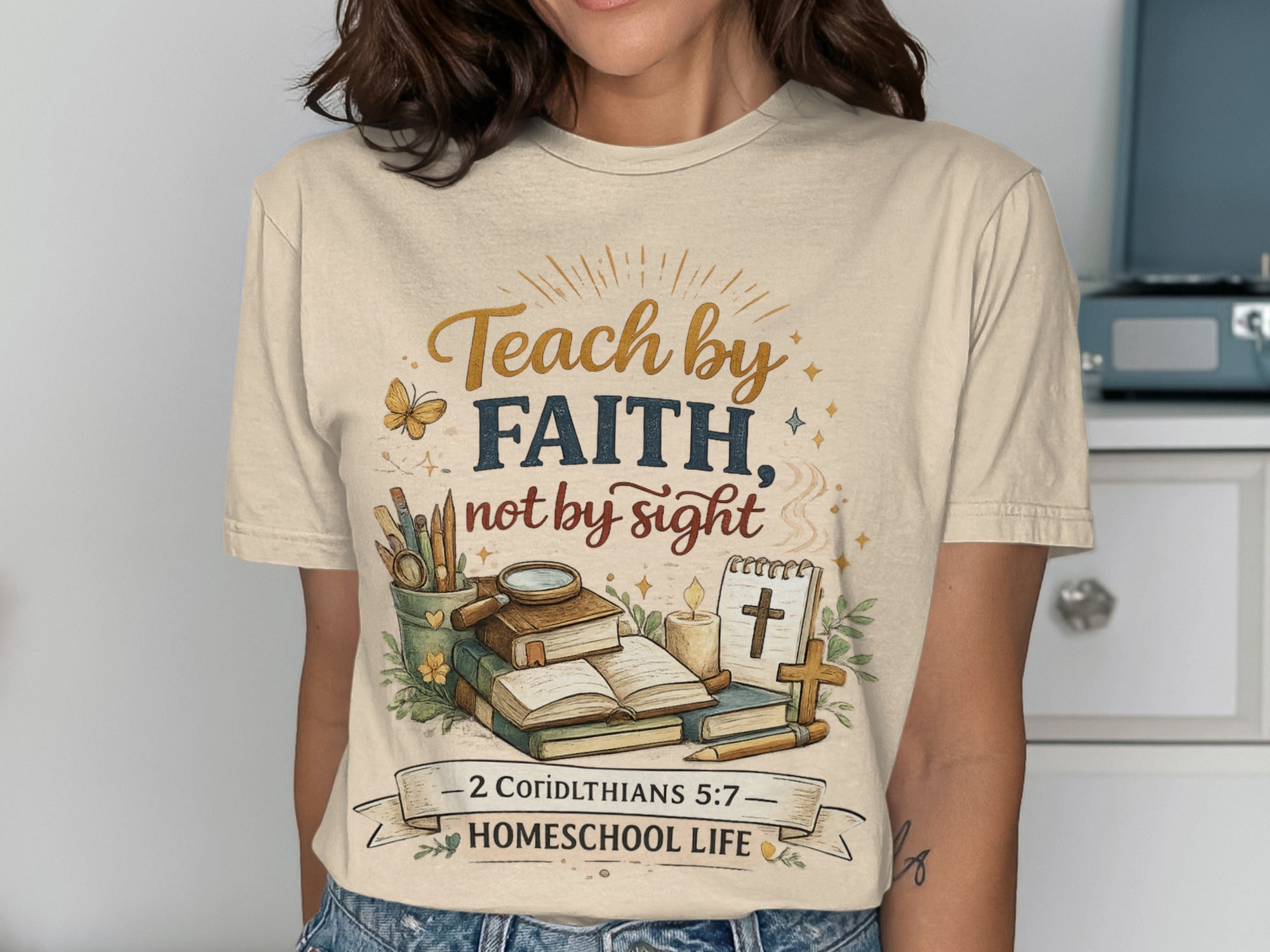 Cream t-shirt with "Teach by Faith, Not by Sight" and homeschool theme graphic.