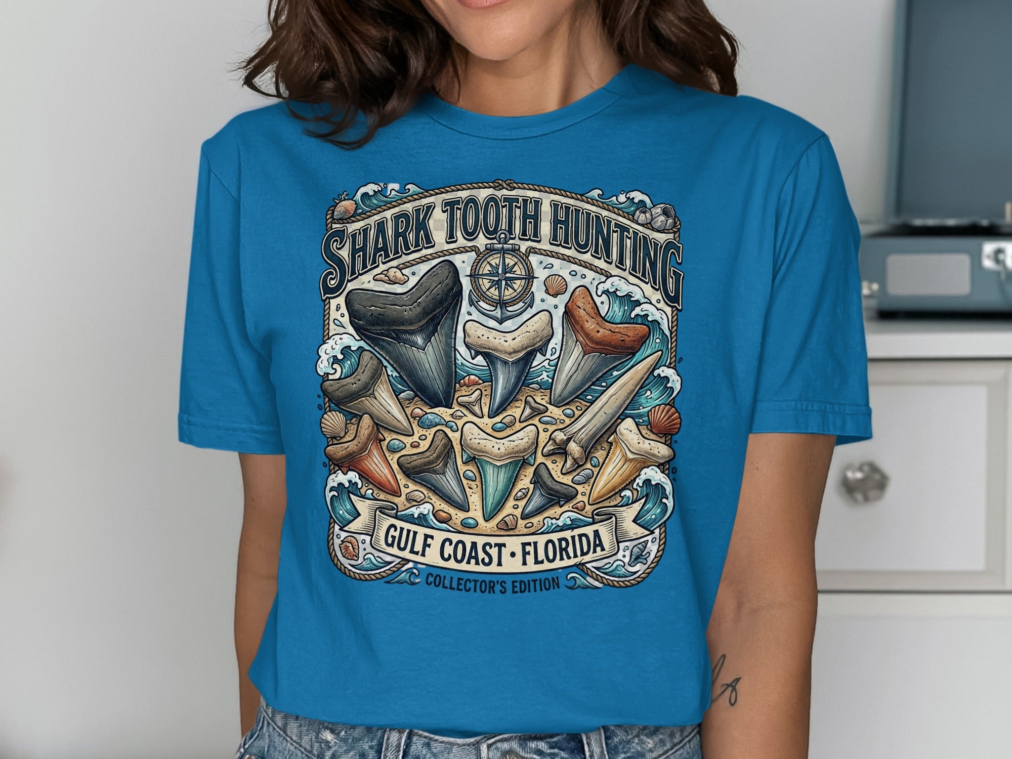 Blue t-shirt with "Shark Tooth Hunting Gulf Coast Florida" graphic and assorted shark teeth.